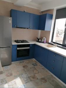 cocina con armarios azules, fogones y fregadero en Apartament Central Craiova, en Craiova