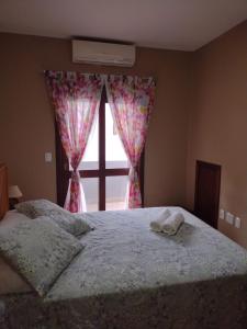 a bedroom with a bed with a window with curtains at Sobrado aconchegante em Nova Petrópolis-RS perto de Gramado in Nova Petrópolis