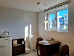 a kitchen with a table and a refrigerator and a window at Hotel Lana in Gangneung