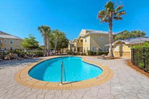 a swimming pool in a yard with palm trees and houses at Topsail Village 422 in Santa Rosa Beach
