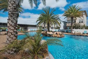 a swimming pool with palm trees in a resort at Beachful Bliss in Santa Rosa Beach