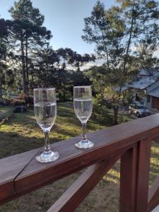 two wine glasses sitting on top of a wooden rail at Sobrado aconchegante em Nova Petrópolis-RS perto de Gramado in Nova Petrópolis