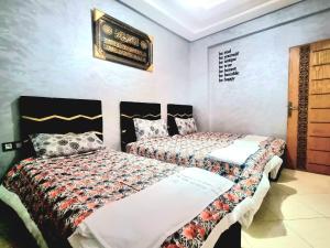 a bedroom with two beds and a sign on the wall at Apprt Ennakhil 2 in El Jadida