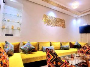 a living room with a yellow couch with colorful pillows at Apprt Ennakhil 2 in El Jadida