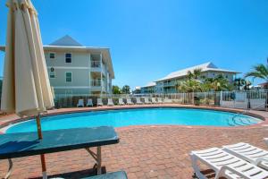 a pool with an umbrella and chairs and a table and chairs at Beachside Villas 332 in Santa Rosa Beach