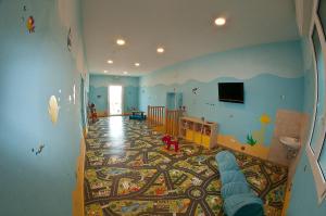 a room with a nursery with a crib and a rug at Hotel Alba D'Oro in Bellaria-Igea Marina