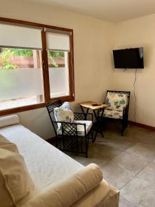 een slaapkamer met een bed, twee stoelen en een tafel bij Departamento M&L in San Martín de los Andes