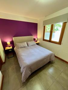 een slaapkamer met een groot bed met paarse muren bij Departamento M&L in San Martín de los Andes