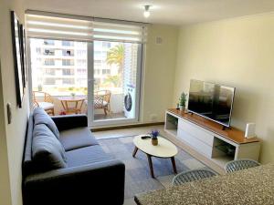 a living room with a couch and a tv and a table at Cómodo Departamento Sector Puerta del Mar in La Serena