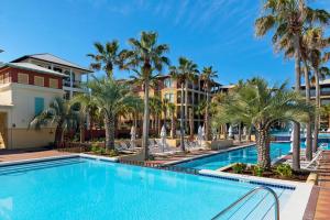 a swimming pool with palm trees and condos at The Eagles Nest in Rosemary Beach