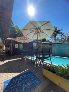 a patio with tables and umbrellas next to a pool at Canoa Abraão in Abraão