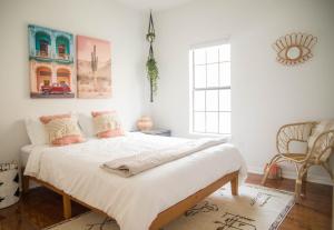 Un dormitorio con una gran cama blanca con almohadas. en Cozy Bohemian Bungalow, en Houston