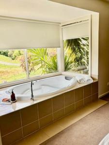 a bath tub in a room with a large window at Daylesford Spa Villa One in Daylesford +19 photos