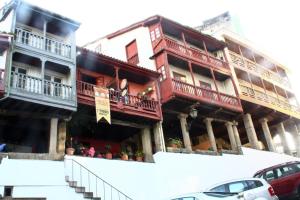 a building with red balconies and cars parked in front of it at Hotel Garelos Betanzos in Betanzos
