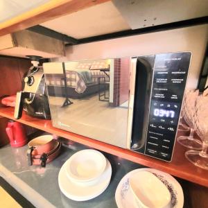 a microwave oven with white plates on a counter at Perfeito Studio 20 in Poços de Caldas