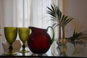 three wine glasses and a red vase on a table at Appartamento XII Gennaio 3 in Palermo