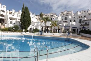 een groot zwembad met witte gebouwen op de achtergrond bij Benalmadenapartments BBQ Evita Beach Club in Benalmádena