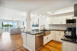 a kitchen with white cabinets and black counter tops at Land's End 5-204 Gulf-Bay Front - Premier in St. Pete Beach