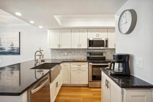 a kitchen with white cabinets and a clock on the wall at Land's End 5-204 Gulf-Bay Front - Premier in St. Pete Beach