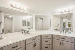 a white bathroom with two sinks and two mirrors at Land's End 5-204 Gulf-Bay Front - Premier in St. Pete Beach