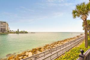 a retaining wall next to the water with a palm tree at Land's End 5-204 Gulf-Bay Front - Premier in St. Pete Beach