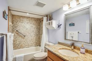 a bathroom with a sink and a tub and a toilet at Pelican Pointe 2C in Clearwater Beach