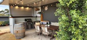 a patio with a table and chairs and a barrel at Equestrian Farm Stay in One Tree Hill