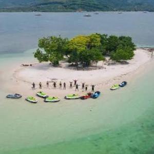 un groupe de personnes debout sur une plage avec des bateaux dans l'établissement Gili Camp X - Kedis Island, à Gili Sudak 4 autres photos