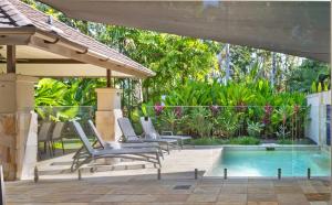 a patio with chairs and a swimming pool at SeaEden Port Douglas Apartments in Craiglie