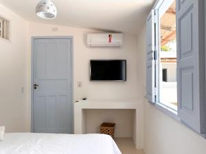a bedroom with a bed and a tv on a wall at Pousada Vilab in Arraial d'Ajuda