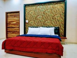 a bedroom with a red bed with a painting on the wall at PANCHHI'S NEST Villa in Amritsar