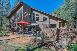 a wooden house with a patio and umbrella at Red Cedar - Unit 30 in Sunriver