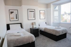 two beds in a room with white walls and windows at Lymer House in Wolverhampton