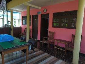 a room with a table and chairs and a pink wall at Travellers Home in Matara