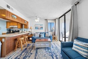 ein Wohnzimmer mit einer blauen Couch und einer Küche in der Unterkunft Gulf Shores Surf & Racquet 716A in Gulf Shores