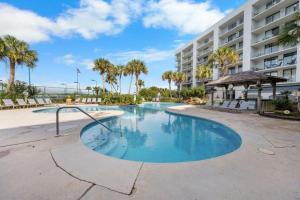ein Swimmingpool vor einem Gebäude mit Palmen in der Unterkunft Gulf Shores Surf & Racquet 716A in Gulf Shores