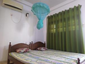 a bedroom with a bed with a green curtain at Travellers Home in Matara