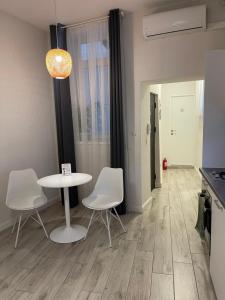 a room with a table and white chairs and a kitchen at Gabriela Studio Central by Gabriela Apartamente in Satu Mare
