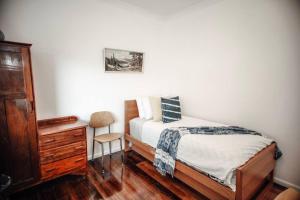 a bedroom with a bed and a wooden dresser at Craypot Cottage in Port Campbell