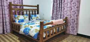 a wooden bed in a room with purple curtains at LakeSide Beach in Kigoma