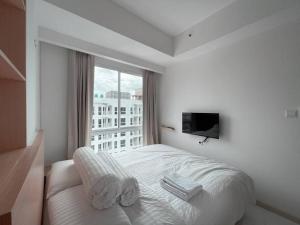 a white bedroom with a bed and a window at Bangulbobo 2br tower Ishikawa in Sungaitahang