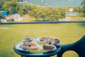 a table with two plates of food and two cups of coffee at Jade City Hotel in Pokhara