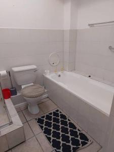 a bathroom with a tub and a toilet and a rug at Azzure Apartments 4 sleeper Strand in Strand