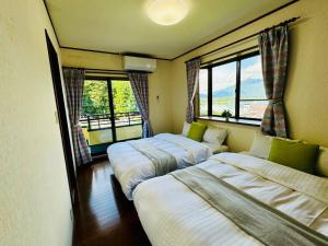 zwei Betten in einem Zimmer mit zwei Fenstern in der Unterkunft LakeView-Rental Villa Engawa House in Fujikawaguchiko