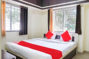 une chambre avec un grand lit avec des oreillers rouges dans l'établissement Hotel OThe Guesthouse, à Kharakvasla