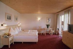 a bedroom with a bed and a table and a tv at Hotel Ansitz Haidenhof in Lienz