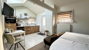 a bedroom with a bed and a desk and a kitchen at Slapen bij de Zeeuwse Lala in IJzendijke