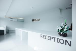 a white room with a vase of flowers on a wall at Minitel at Hatyai in Ban Khlong Wa