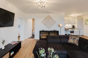 a living room with a black couch and a kitchen at Das MONTI - Deluxe in Stendal