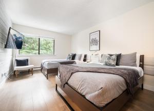 a bedroom with two beds and a chair and a window at Creekside Oasis 4 Beds Pool and Hot Tub in Whistler